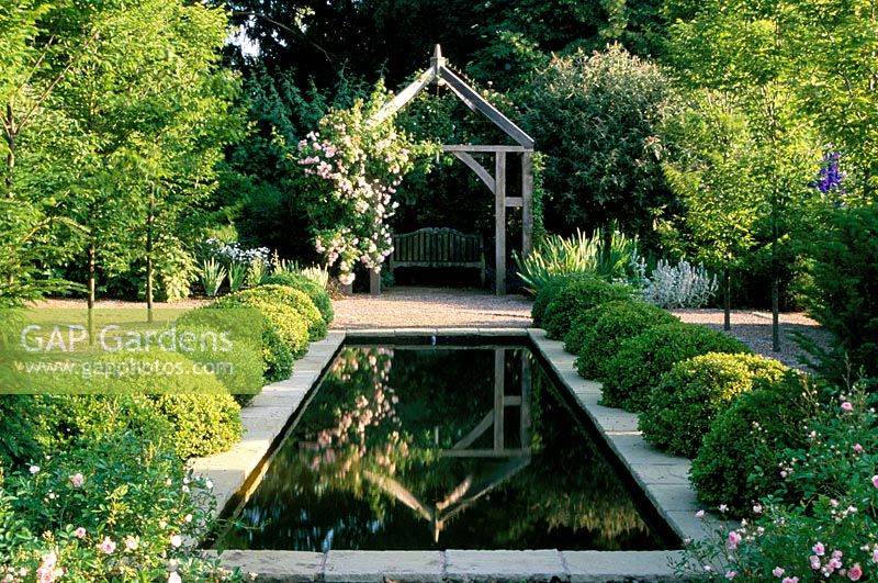 Formal pond flanked by box topiary balls at Wollerton Old Hall in Shropshire