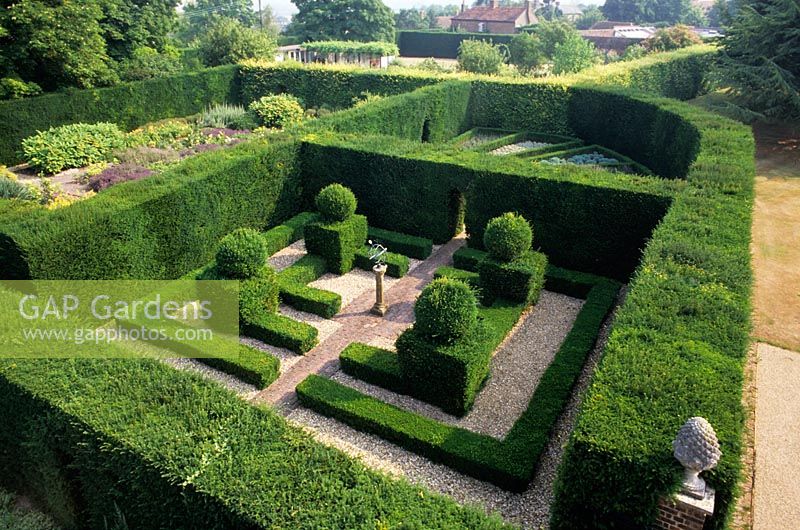 Taxus - Yew hedges surrounding garden rooms with topiary and hedging at The Manor House Bledlow in Buckinghamshire