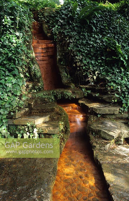 Stepped waterfall in sloping garden at Chalice Well Garden in Glastonbury in Somerset