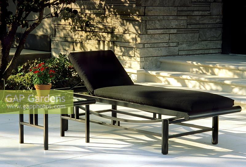 Black sunlounger and glass topped table on patio in San Francisco, USA