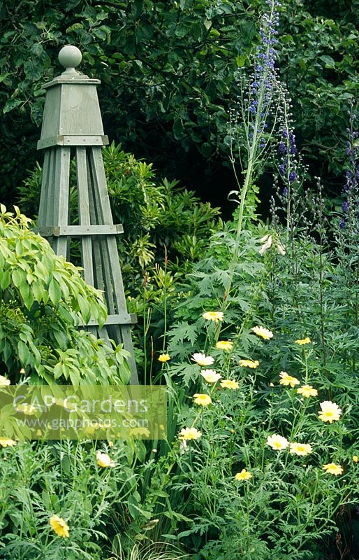 Green wooden obelisk in herbaceous border