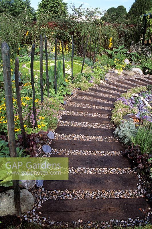 Garden path made from old railway sleepers with gravel fill in