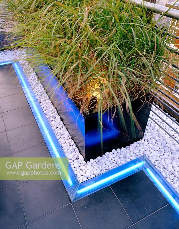 Roof garden detail, container, white pebbles, neon strip lighting and black slate paving 