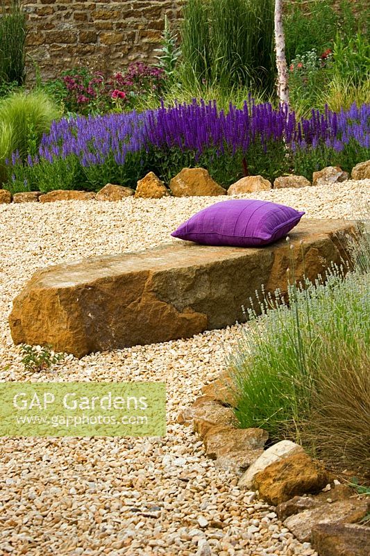 Gravel garden with rock seat, purple cushion and Salvia 'Wesuwe'