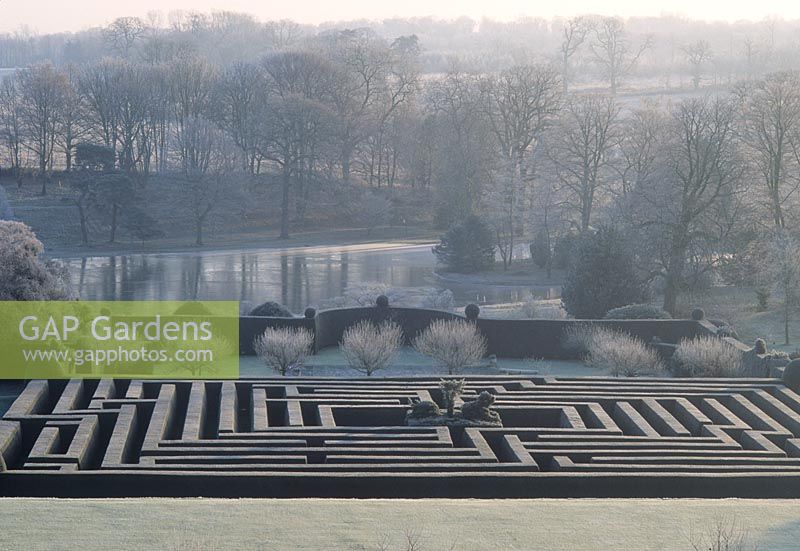 View down onto formal clipped maze, pond, trees with winter frost - Hatfield House