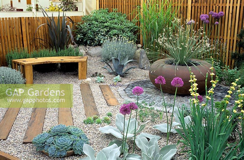 Gravel garden with timber bench and large rusty container