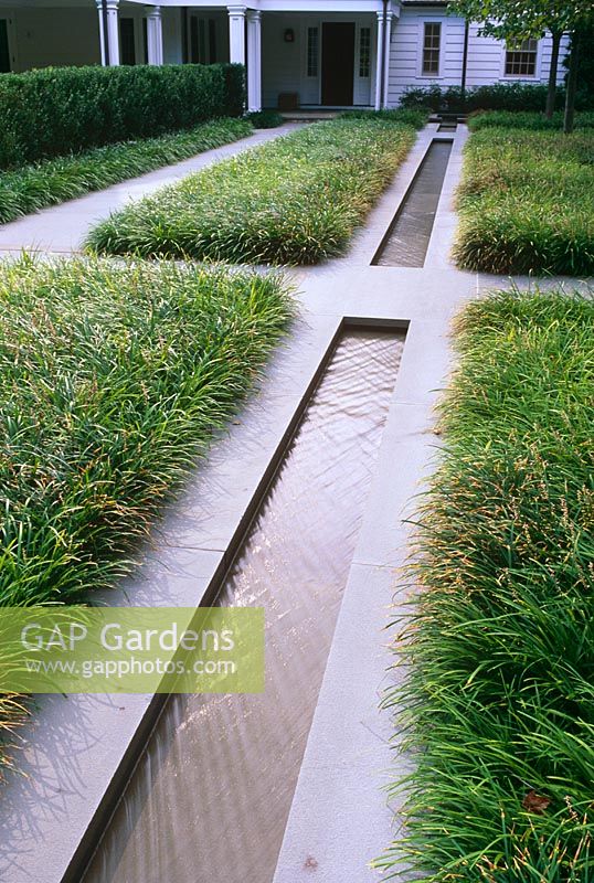 Contemporary water rill with grasses, paths and house in background - The Odrich Garden, Greenwich, Connecticut, USA 