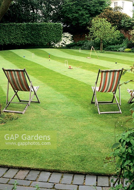 Immaculate lawn with stripes laid out for croquet and relaxation 