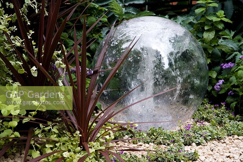 Glass ball water feature with phormium. Garden - The Way Forward, Designers - Zoe Cain, with Jim Buttress VMH and Jocelyn Armitage, for St Joseph's Hospice and Perennial Gardeners' Royal Benevolent Fund