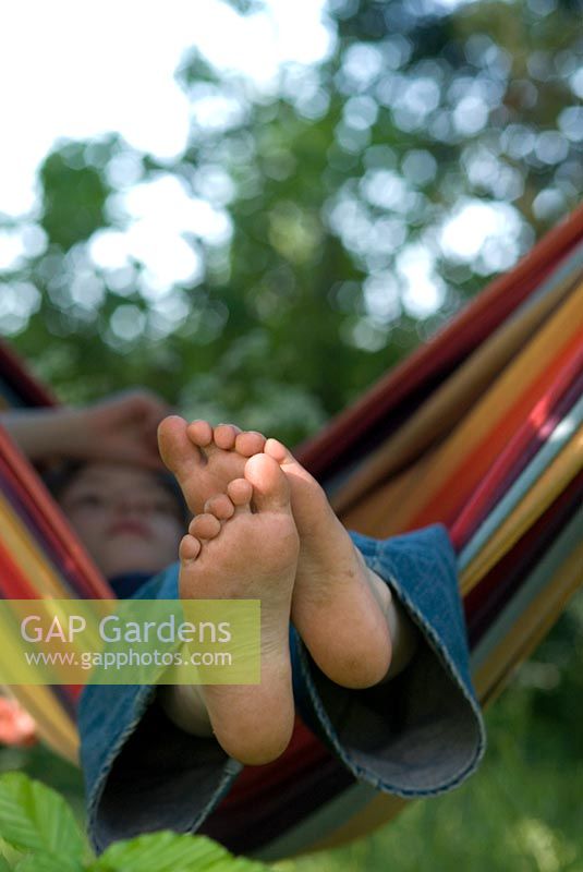 Boy relaxing in a colourful striped hammock