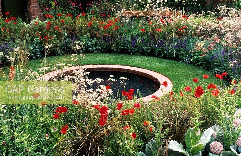 Cottage garden with round brick lined pond surrounded by border of Papaver, Carex, Anthiscus, Salvia and Allium - The Largest Room in the House Garden - Chelsea Flower Show 2008, Sponsors - GMI Property Company, The Royal British Legion, Toc H

