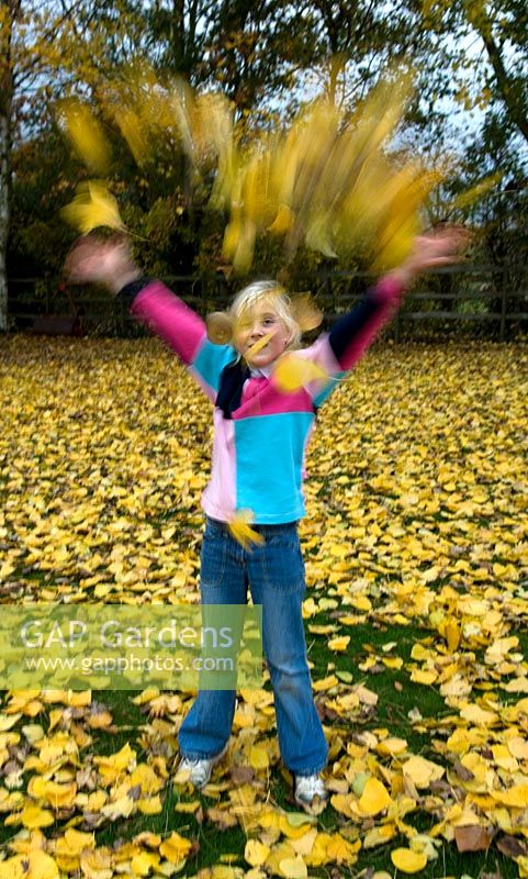 Girl throwing autumn leaves in garden - Pannells Ash Farm West Essex