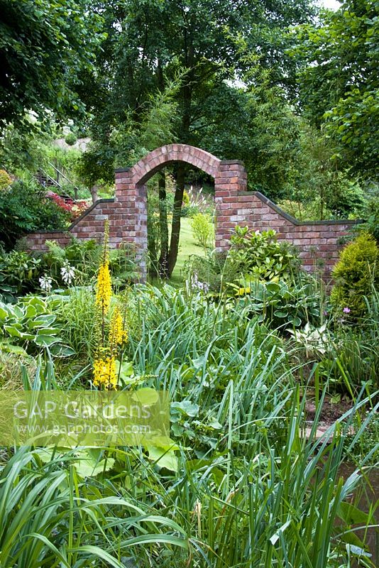 Brick arch and brookside planting at Honeybrook House Cottage, Worcestershire