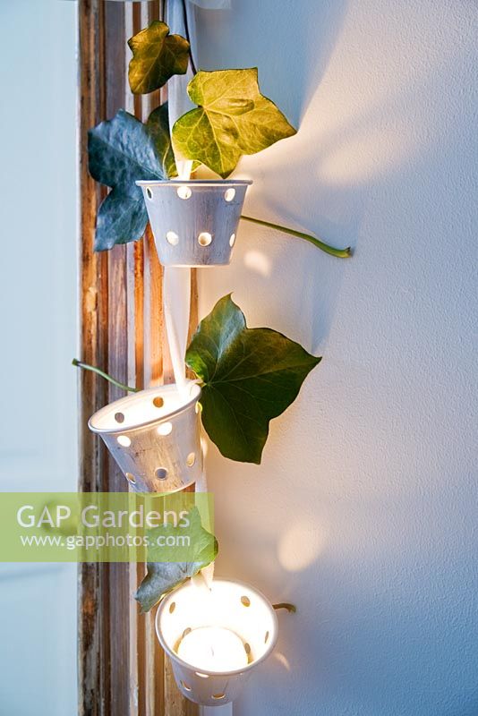 Tealight holders decorated with ivy leaves hanging on door frame