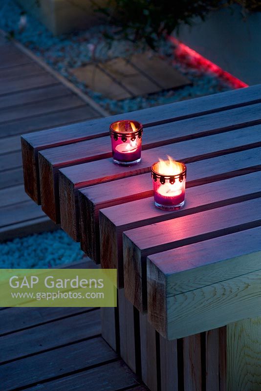 Ornate candle holders with lit candle on western red cedar bench - Roof garden, Holland Park, London 