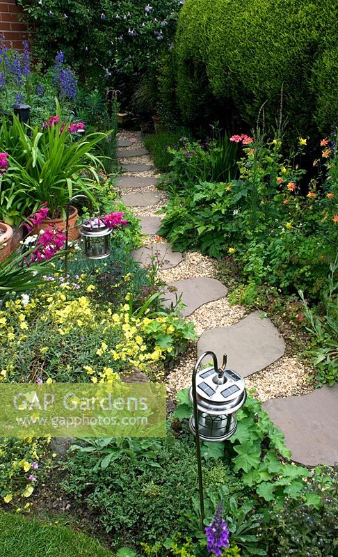 Stepping stones and gravel pathway lined with lanterns and plantings of Gladiolus communis Byzantinus and Aconitum - Cross Villas, Shropshire