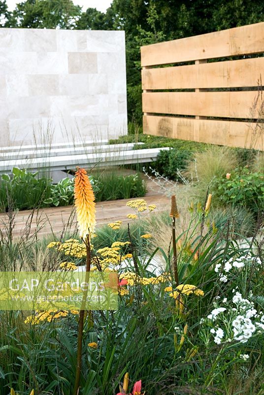 Hemerocallis, Achillea 'Terracotta', Stipa tenuissima and Kniphofia in The Traveller's Garden with Bradstone - Hampton Court Flower Show 2008