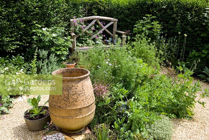 Wooden bench in gravel area with empty terracotta urn with Nigella, Alliums and Geranium plamatum - Eldenhurst