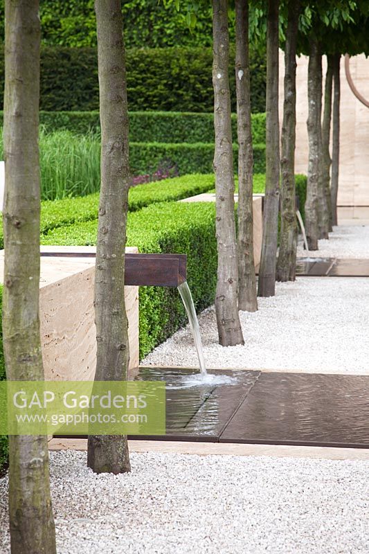 Contemporary water feature with rusted steel chute and shallow pool, under avenue of Carpinus betulus - The Laurent-Perrier Garden, Sponsored by Champagne Laurent-Perrier - Gold medal winner at RHS Chelsea Flower Show 2009