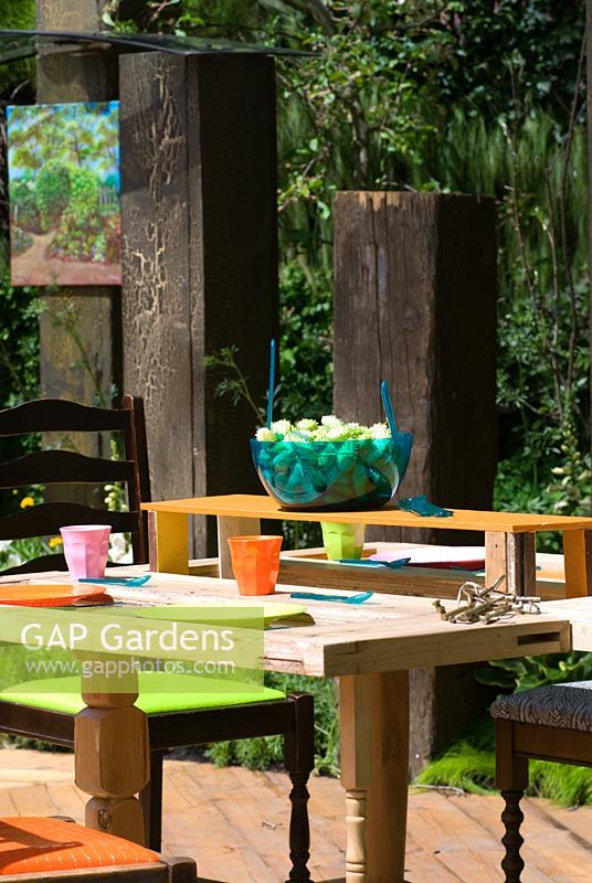 Outdoor dining area with tables and chairs made from recycled materials. The Key Garden, sponsored by Eden Project in partnership with The Homes and Communities Agency, Communities and Local Government, London Employer Accord - Silver medal winner at RHS Chelsea Flower Show 2009