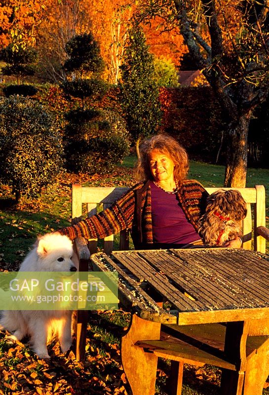 Louise Bendall with dogs 'Berkeley' on left, and 'Blue' in the garden at sunset - Highfield Hollies, Liss, Hampshire
