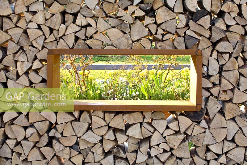 Window in wall of logs with view of Spring garden beyond