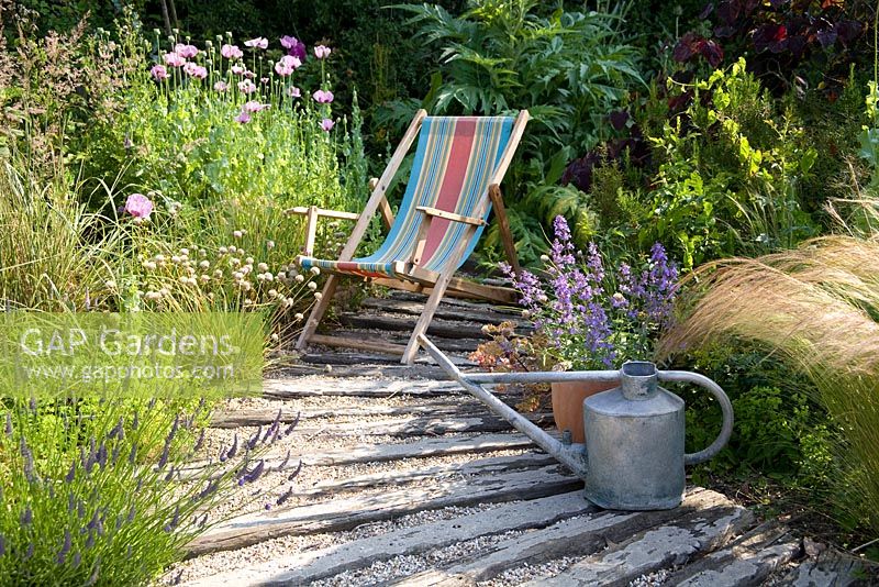 Deck chair in coastal-look garden, with watering can and container with Nepeta