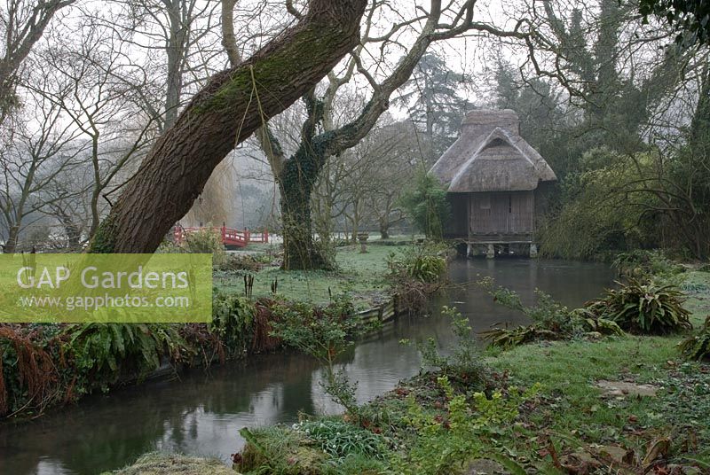 Japanese teahouse and bridge on the river in the woodland garden in frost, 
Heale House Gardens, Wiltshire