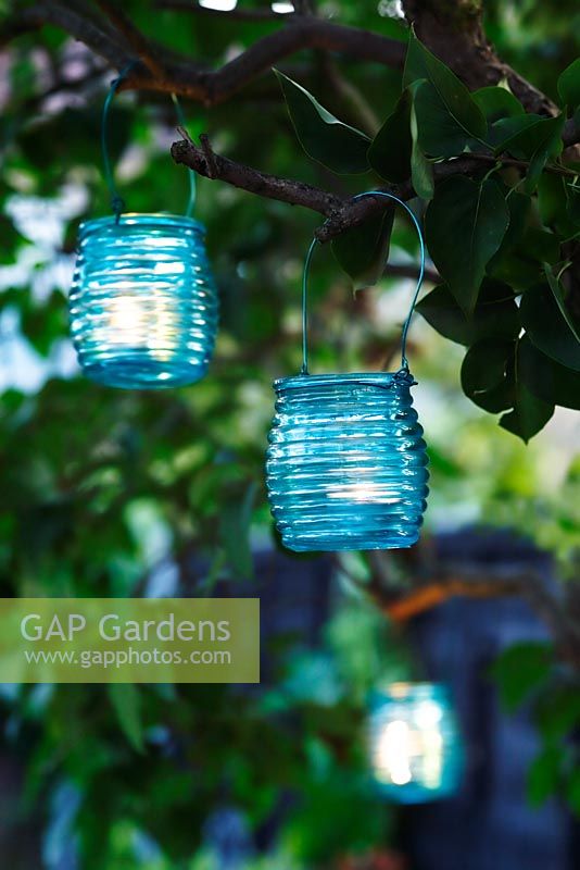 Turquoise glass tealight holders hanging in tree