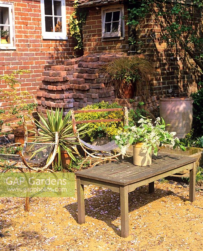 Rustic seating area in gravel courtyard - Charlotte Molesworth's garden, Kent