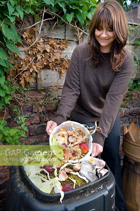Woman emptying kitchen waste into compost bin