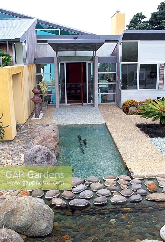Styalised nature including fish swimming in a river complete the front entrance to this art collectors home. Tropical cycads, textures of stones and boulders. Waiheke, New Zealand
