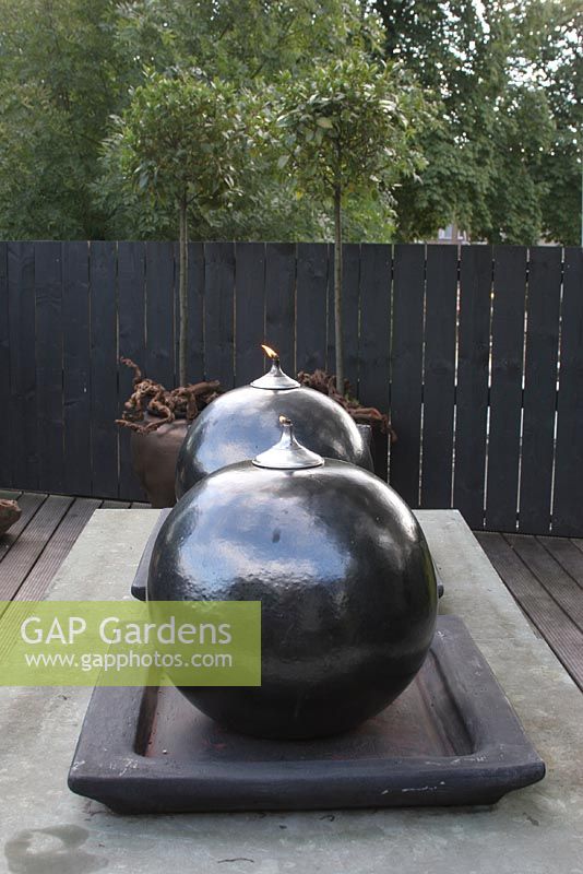 Large spherical oil burners on table on roof terrace in summer. 

