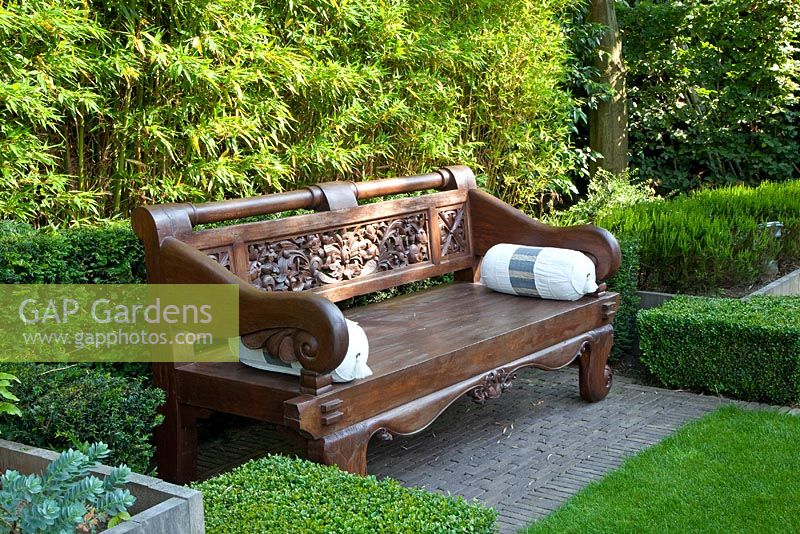 Carved Indonesian bench backed by Bamboo