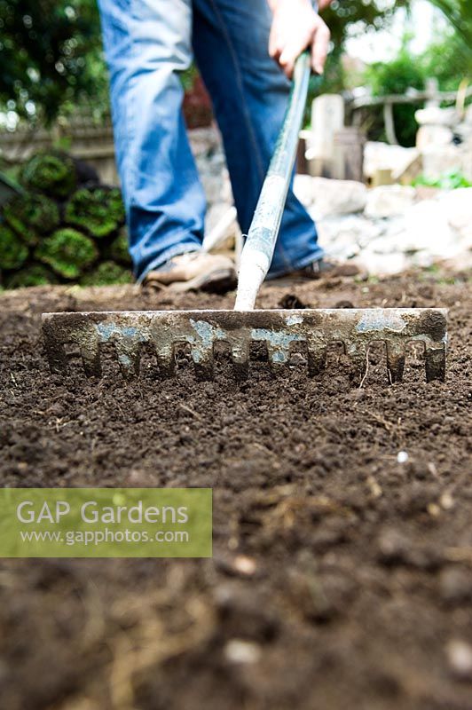 Low angle view of gardener raking soil
