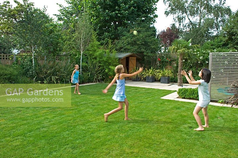 Children playing on lawn in urban garden. Barnes, London
 