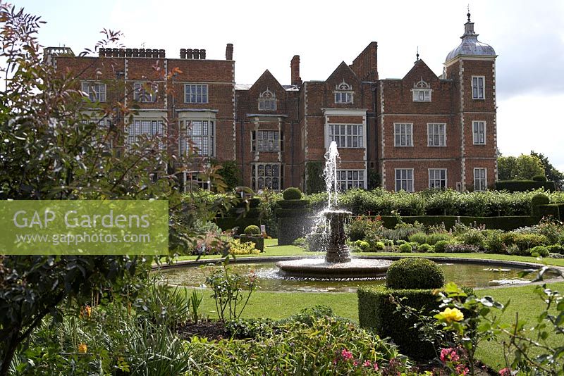 West Parterre in front of house with fountain, topiary and herbaceous borders - Hatfield House, Hertfordshire