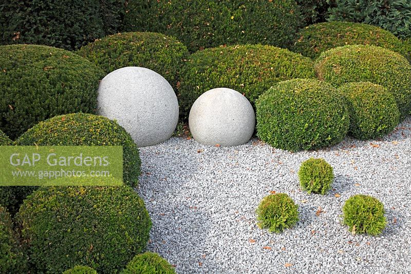 Stone, clipped Buxus and Chamaecyparis spheres in gravel