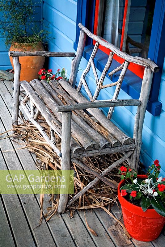 Rustic wooden bench on the veranda of a blue painted cottage. Impatiens in red pot. No. 11, Christchurch, New Zealand