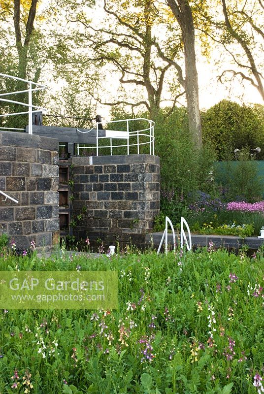 Lock gate next to wildflower area with Lychnis flos-cuculi and Digitalis in the background. The HESCO Garden, Gold medal winner at RHS Chelsea Flower Show 2010 