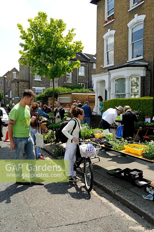 People at plant sale including lady with bike, urban street in Hackney, London, UK