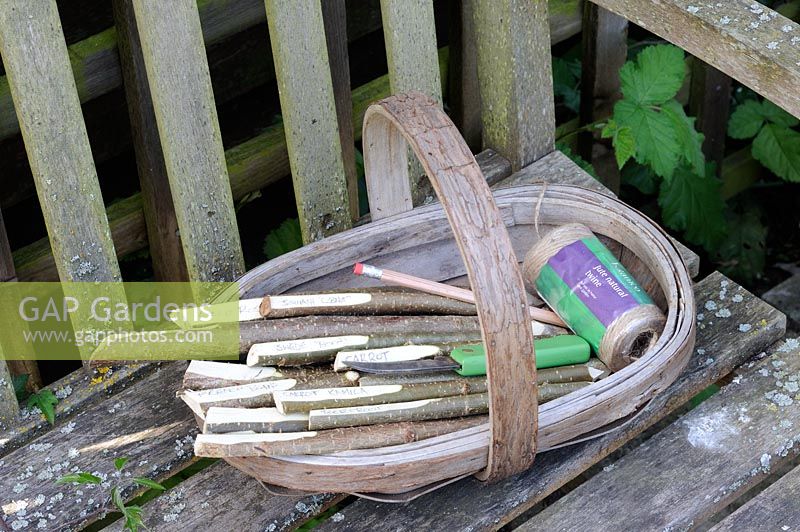 Garden seat with wooden trug of hazel stick markers, garden twine and seeds 