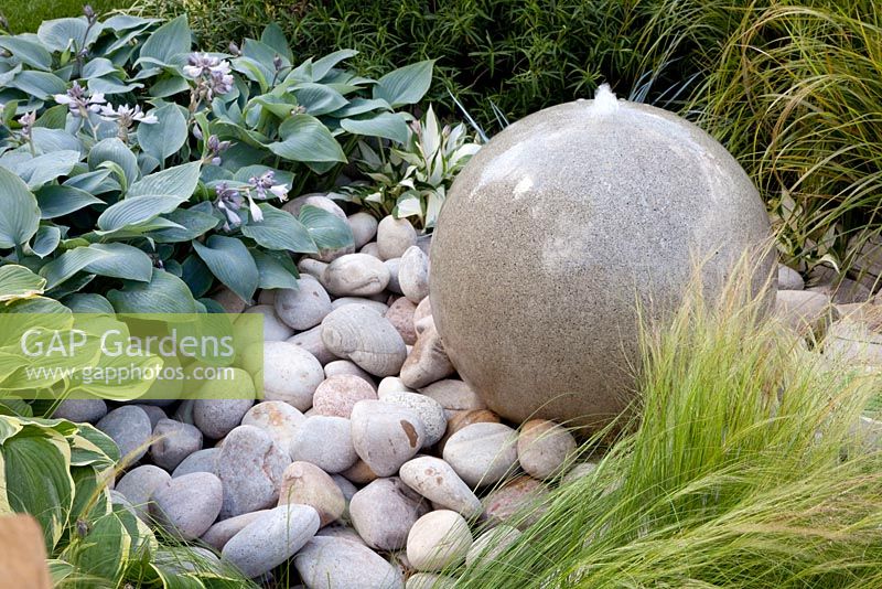 Round stone water feature amongst Hosta and Stipa tenuissima - 'The Urban Retreat', Bronze medal winner, RHS Hampton Court Flower Show 2010 