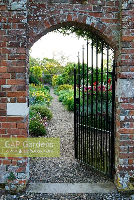 Gateway into the walled kitchen garden reveals the double herbaceous borders. Edmondsham House, Cranborne, Wimborne Minster, Dorset, UK
