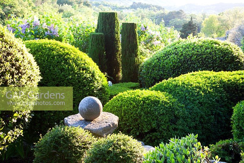 Topiary and stone finial in La Louve garden, Provence, France
