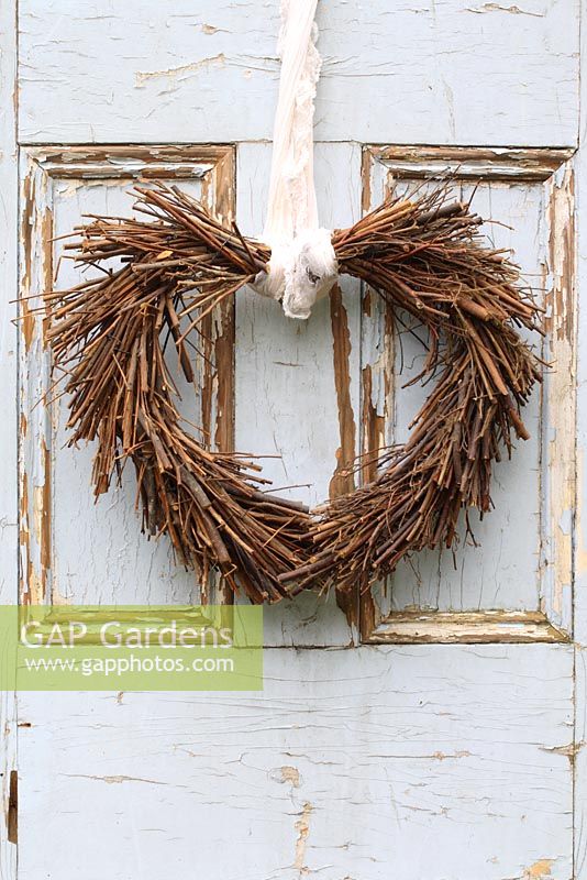 Christmas heart shaped wreath hanging on rustic door 