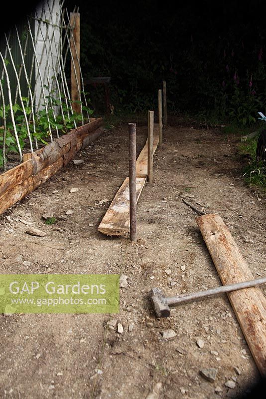 Building a raised bed - Knock in posts against a line at intervals to support the side planks 