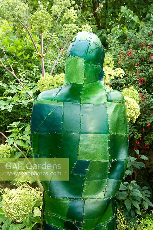 Green resin figure in border with Angelica behind. Yulia Badian garden, London, UK 
 