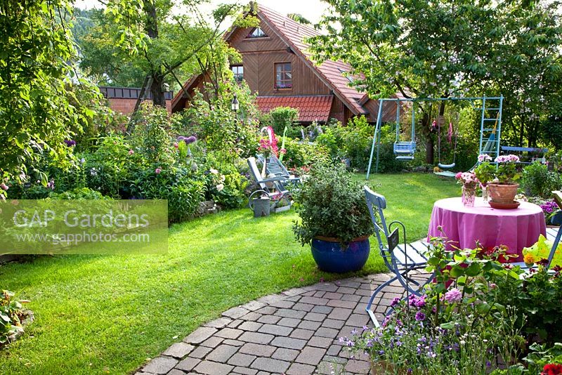 Patio in country garden with childrens play equipment.