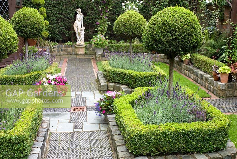 Secluded parterre garden with paths and walls made of small reclaimed cobbles, station platform tiles and bricks, parterre with Buxus sempervirens - Box hedges, Lavandula angustifolia 'Hidcote' and Thuja topiary standards and classical statue - Brocklebank Road, Southport, Lancashire NGS 
